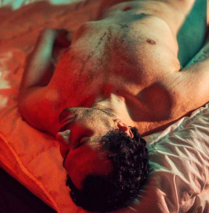 high angle view of a nude man sleeping in color light